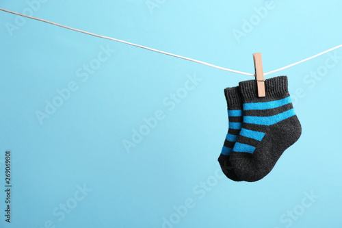Small socks hanging on washing line against color background, space for text. Baby accessories