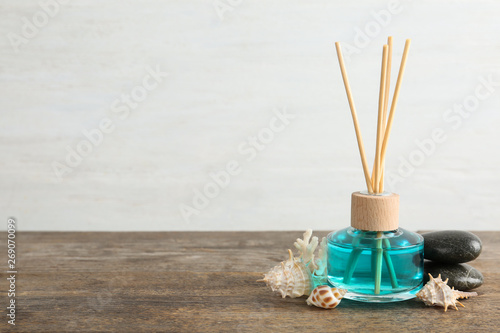 Aromatic reed freshener, spa stones and sea shells on wooden table against light background. Space for text