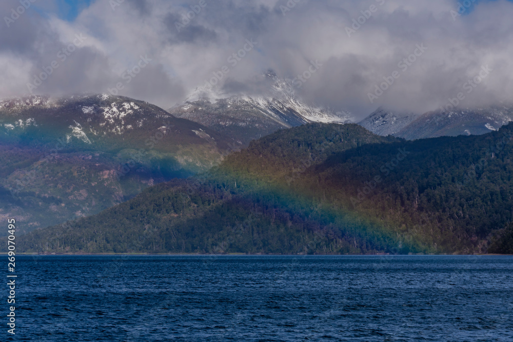 Scene view of a colorful rainbow over a lake against Andes mountains, Los Alerces National Park, Argentina