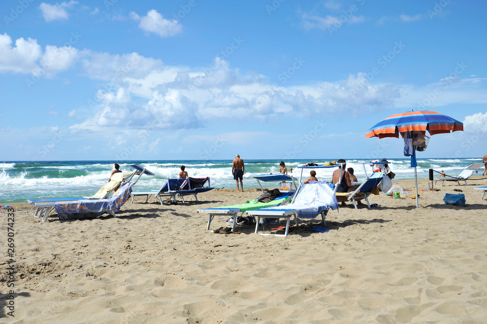 Relaxed people on the Sabaudia beach for the summer holidays. The Circeo Mountain on the background. Sabaudia, Lazio, Italy. Relaxed people on the Sabaudia beach for the summer holidays. The Circeo Mountain on the background. Sabaudia, Lazio, Italy.