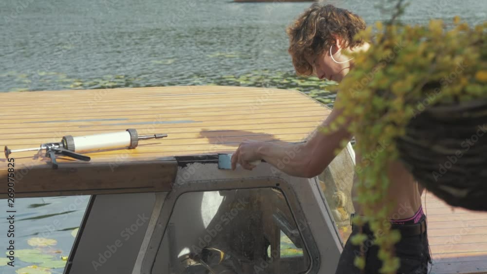 Young working sealing wooden boat cabin roof to prevent leaks using