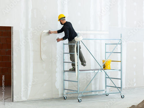 Valokuva worker plastering gypsum board wall.