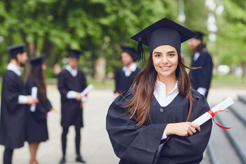 A young female graduate against the background of university graduates.