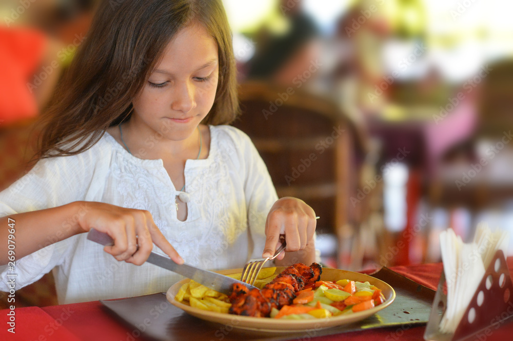 Portrait of little girl eating in cafe