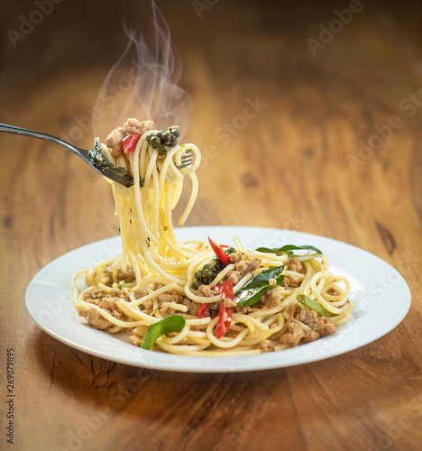Spaghetti Stir Fried With Spicy Pork in the dish on the wooden table