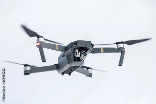 the quadcopter of gray color with the camera in flight against