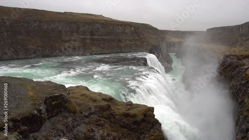Beautiful Iceland Waterfall with cloudy skies and rocks and grass