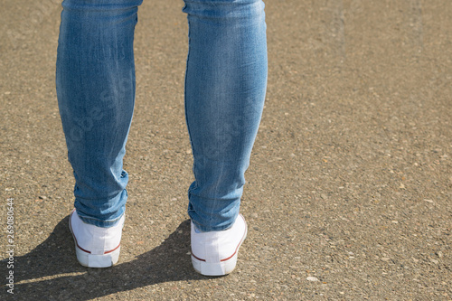 female legs in white sneakers
