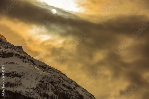 Yellow colored Sunset in Alps. Sun is covered by clouds. photo