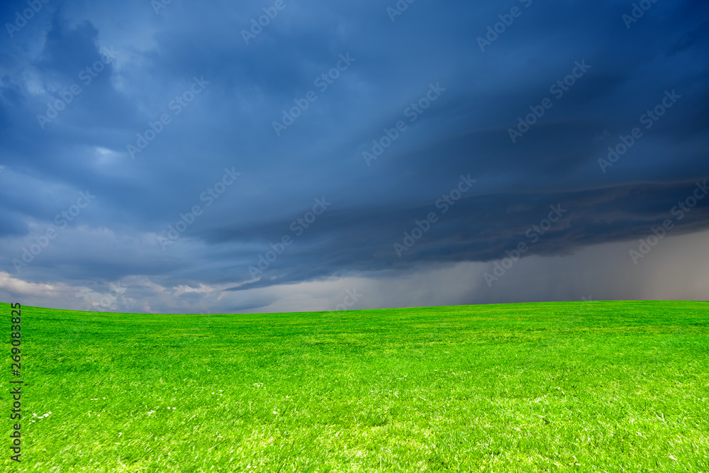 Storm clouds over a green meadow in the spring season. Natural background.