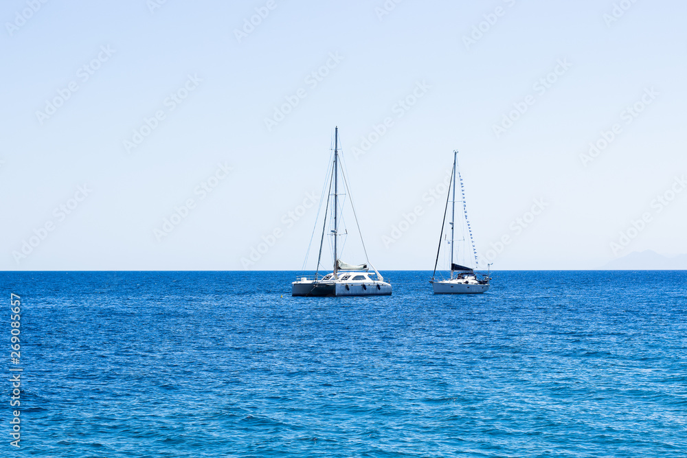 two white yachts on Mediterranean sea calming blue water surface near Malta shoreline beach, summer cruise vacation concept photography with empty copy space