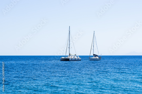 two white yachts on Mediterranean sea calming blue water surface near Malta shoreline beach, summer cruise vacation concept photography with empty copy space
