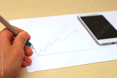 Graph on paper. Sketches of financial strategies and achievements. Smartphone.