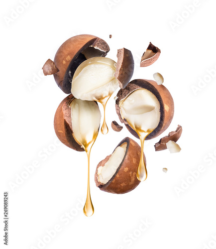 Photos Oil dripping from crushed macadamia nuts on a white background.
