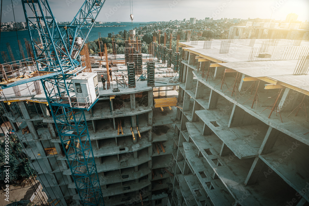 Construction of new building with crane and workers. Concrete pouring reinforcement in formwork on roof Construction of new building with crane and workers. Concrete pouring reinforcement in formwork on roof