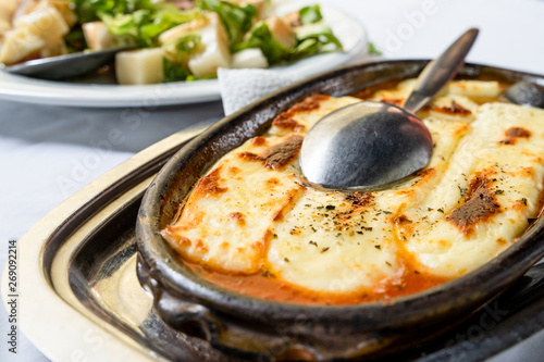 Baked cheese with paprika in a clay pot on the table, traditional serbian food