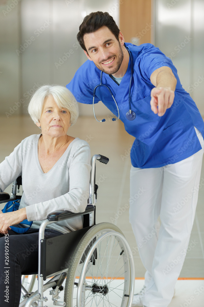 male nurse supporting happy disabled senior woman in a wheelchair male nurse supporting happy disabled senior woman in a wheelchair