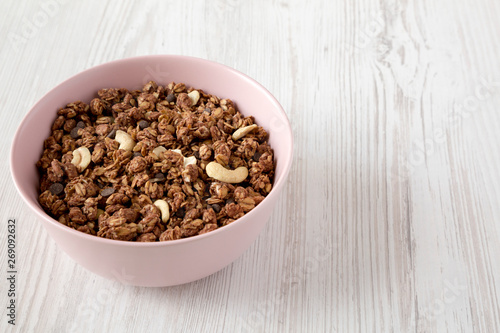 Homemade chocolate granola with nuts in a pink bowl, side view. Copy space.