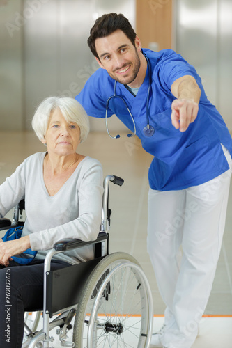 male nurse supporting happy disabled senior woman in a wheelchair