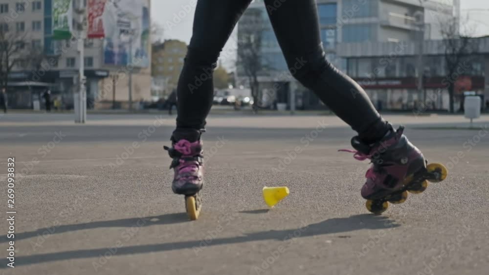 Close up of young woman goes rollerblading. Outdoor activities in summer. Woman rides on roller skates and whirl Close up of young woman goes rollerblading. Outdoor activities in summer. Woman rides on roller skates and whirl