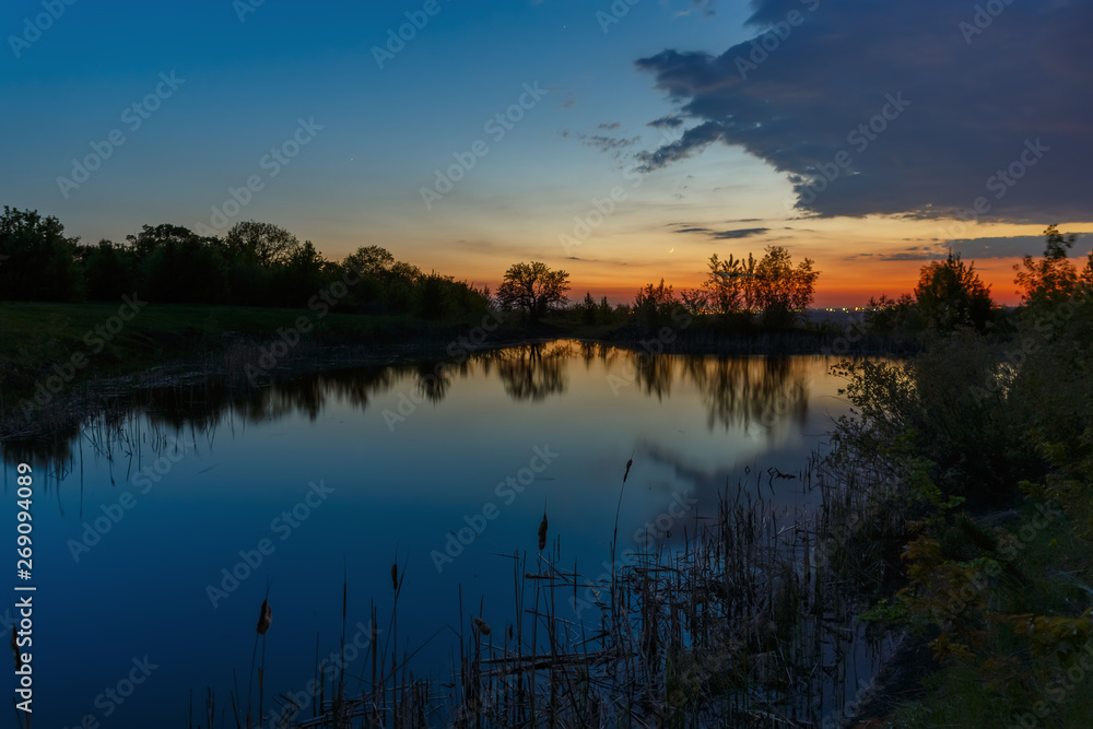 The sky with bright clouds lit by the sun after sunset over the lake.