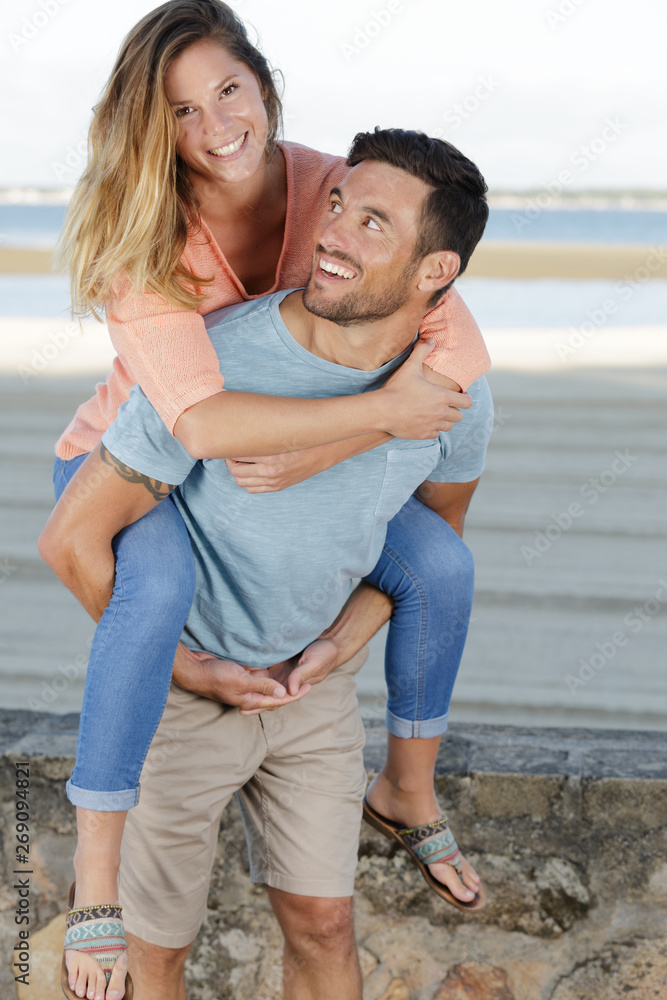 man giving his girlfriend a piggy back on the beach man giving his girlfriend a piggy back on the beach