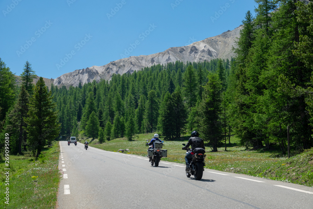 Travelers on motorbikes enjoy a scenic road trip in the picturesque French Alps.
