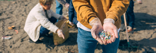 Detail of young man hands showing microplastics on the beach photo