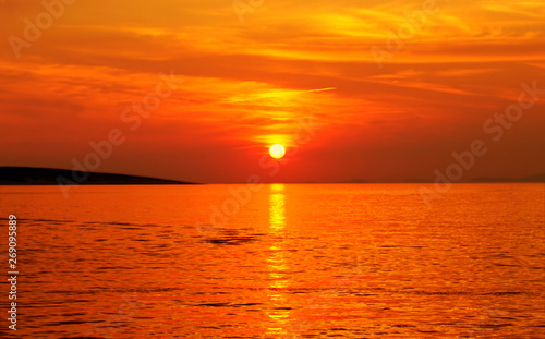 Sunset in vivid orange color on the amazing seascape in hot summer day