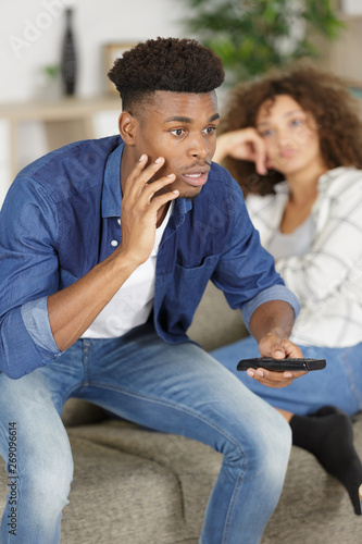 portrait of man watching tv while his girlfriend is upset
