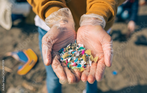 Detail of hands showing microplastics on the beach photo