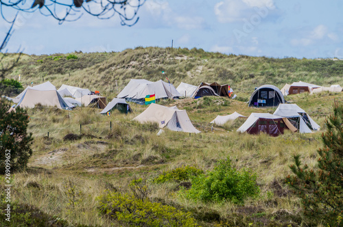 Typical Dutch Vlieland island tent camp of hippies amid of dunes and shrub vegetation with flags waving photo