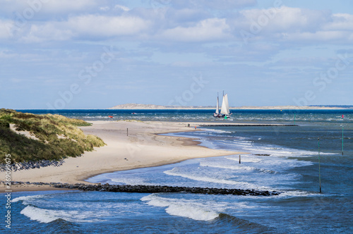 North sea seascape of seaside on Vlieland island with ground swell blue sea and big sailing vessel approaching the coast photo