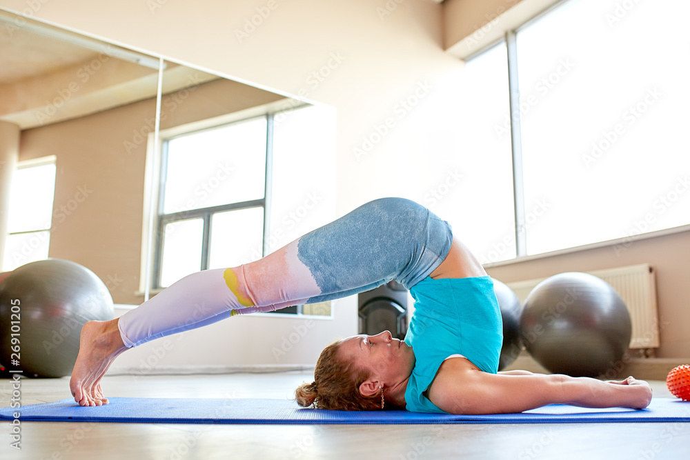 Great progress. Young beautiful woman in sportswear doing stretching in front of window at gym Great progress. Young beautiful woman in sportswear doing stretching in front of window at gym