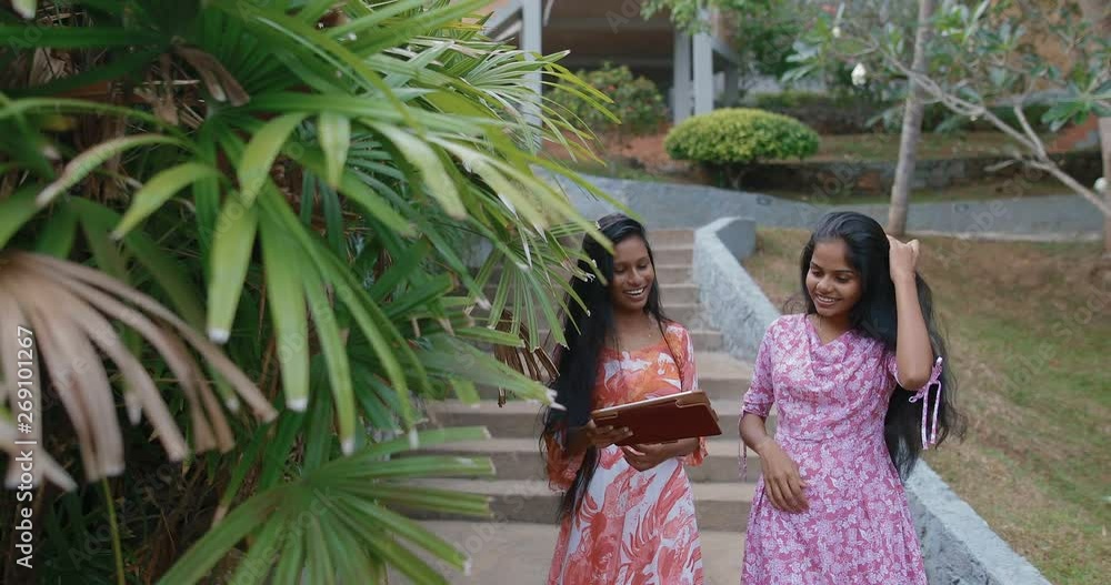 Two Young South Asian attractive girls using tablet computer. Teenagers talking and joking and look natural and happy. in slow motion. Shot on Canon 1DX mark2 4K camera Two Young South Asian attractive girls using tablet computer. Teenagers talking and joking and look natural and happy. in slow motion. Shot on Canon 1DX mark2 4K camera
