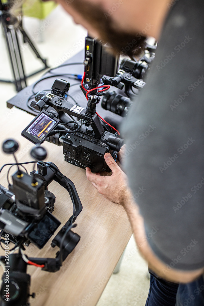 Videographer shooting a film or a television program in a studio with a professional camera, backstage Videographer shooting a film or a television program in a studio with a professional camera, backstage