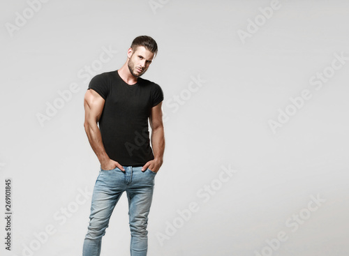 Photography Muscular model sports young man in jeans and black t-shirt on a grey background