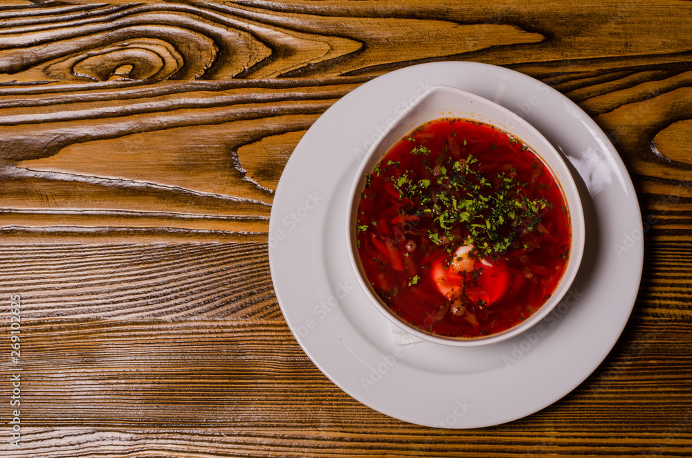 Beats soup, borsch with sour cream; bead and pickles on a background. borsch in a white dish, slices of bread on a wooden cutting board, whole pickles in a wooden dish. Beats soup, borsch with sour cream; bead and pickles on a background. borsch in a white dish, slices of bread on a wooden cutting board, whole pickles in a wooden dish.