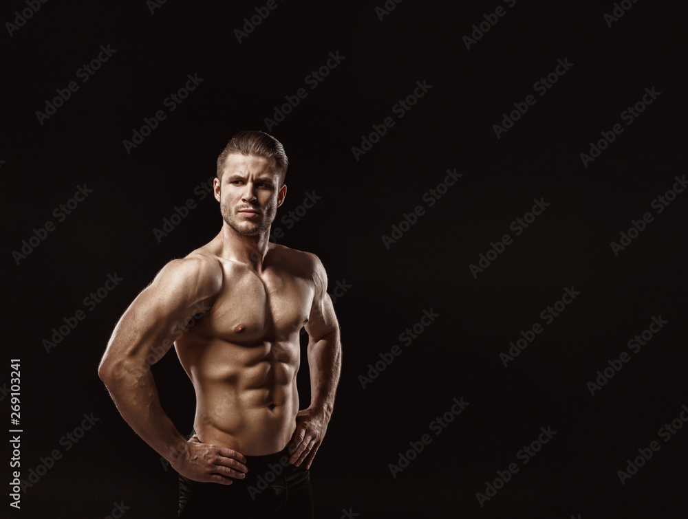 Muscular model young man on dark background. Fashion portrait of strong brutal guy with trendy hairstyle. Sexy naked torso, six pack abs. Male flexing his muscles. Sport workout bodybuilding concept.