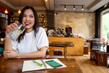 Charming beautiful pretty smile Asian woman mobile phone and take note during rest in coffee shop, happy Asian female girl drinks lemonade and use cell telephone while relaxing in cafe free time