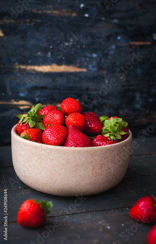 Fresh strawberries in a bowl on wooden background