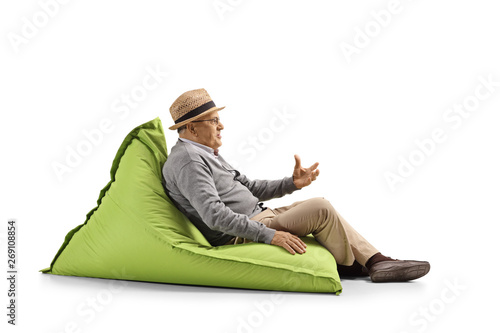 Senior man sitting on a bean-bag and gesturing with hand
