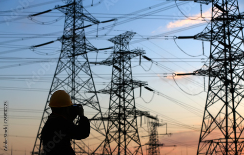A silhouette of a man in front of a high voltage tower