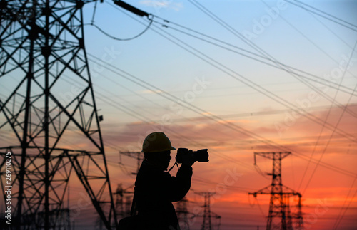 A silhouette of a man in front of a high voltage tower