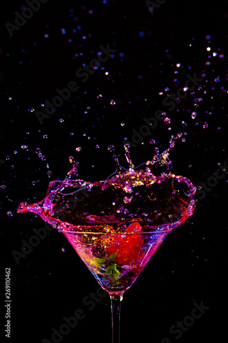 Explosion of Colorful Liquid in Wine Glass with Strawberry. Isolated Over Black Background