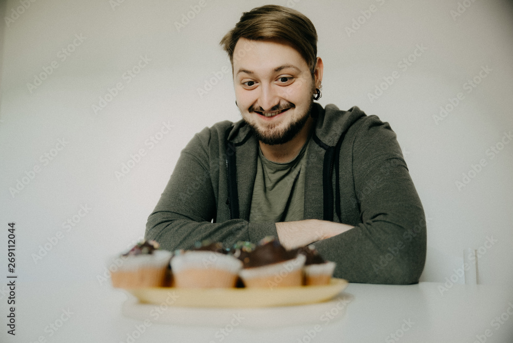 A young hipster on a diet with cupcakes A young hipster on a diet with cupcakes