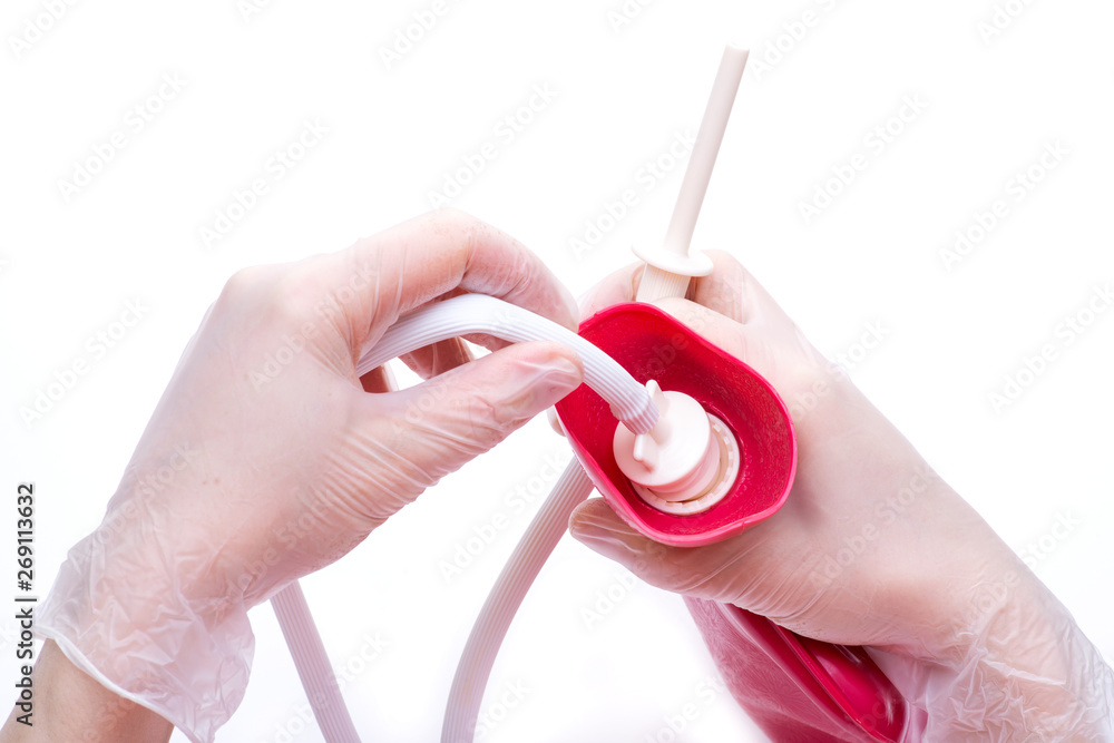 Nurse wearing sterile rubber gloves holds Cleansing Enema Bucket Set on