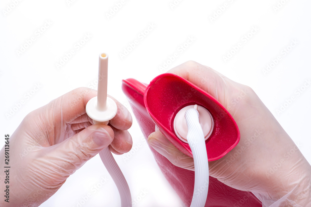 Nurse wearing sterile rubber gloves holds Cleansing Enema Bucket Set on
