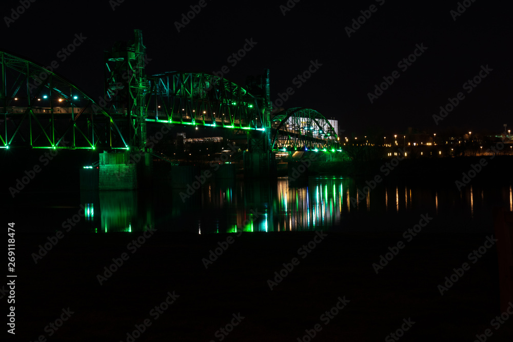 Obraz premium Bridge with colorful lighting at night and park bench in foreground