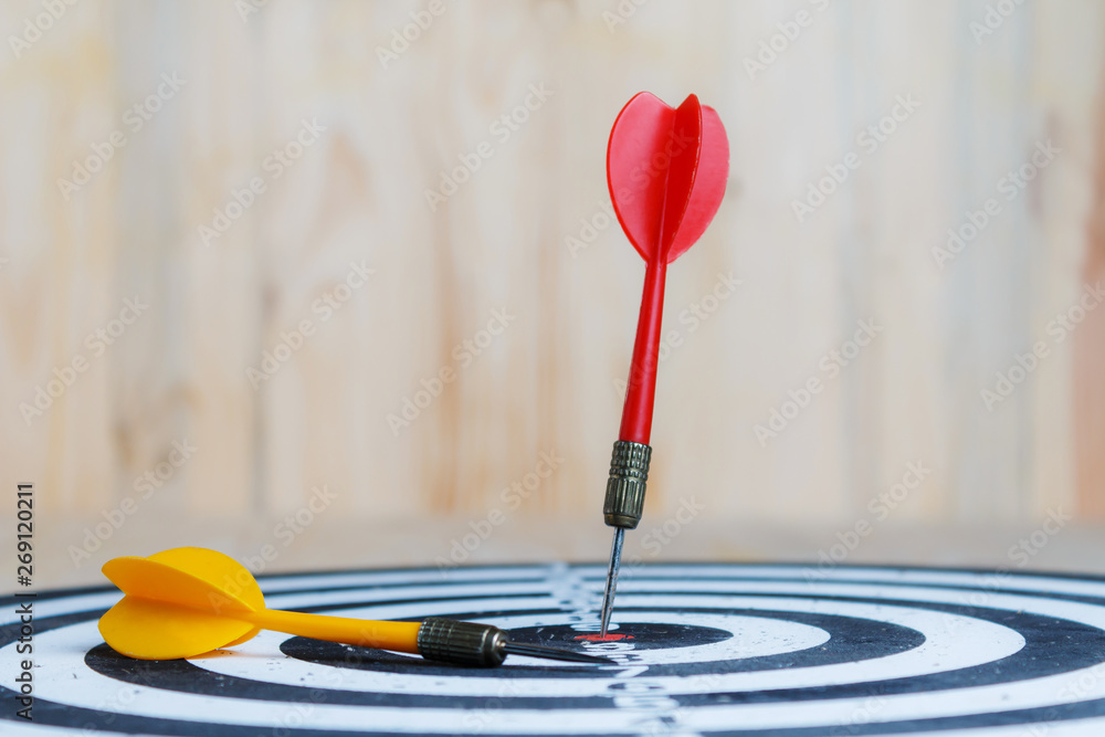 Winner Red dart arrow hit the center target of dartboard and yellow arrow loser metaphor marketing competition concept Winner Red dart arrow hit the center target of dartboard and yellow arrow loser metaphor marketing competition concept